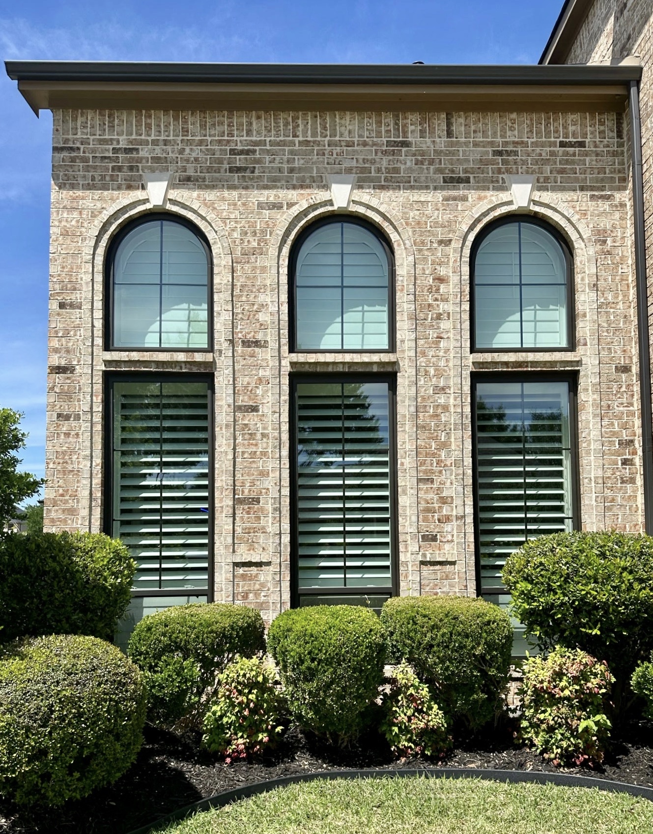 High-performance EcoView arched windows on a white brick home